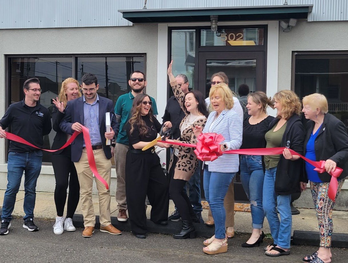 The Prohibited team and community members cutting the red ribbon in front of 502 Juniper Street